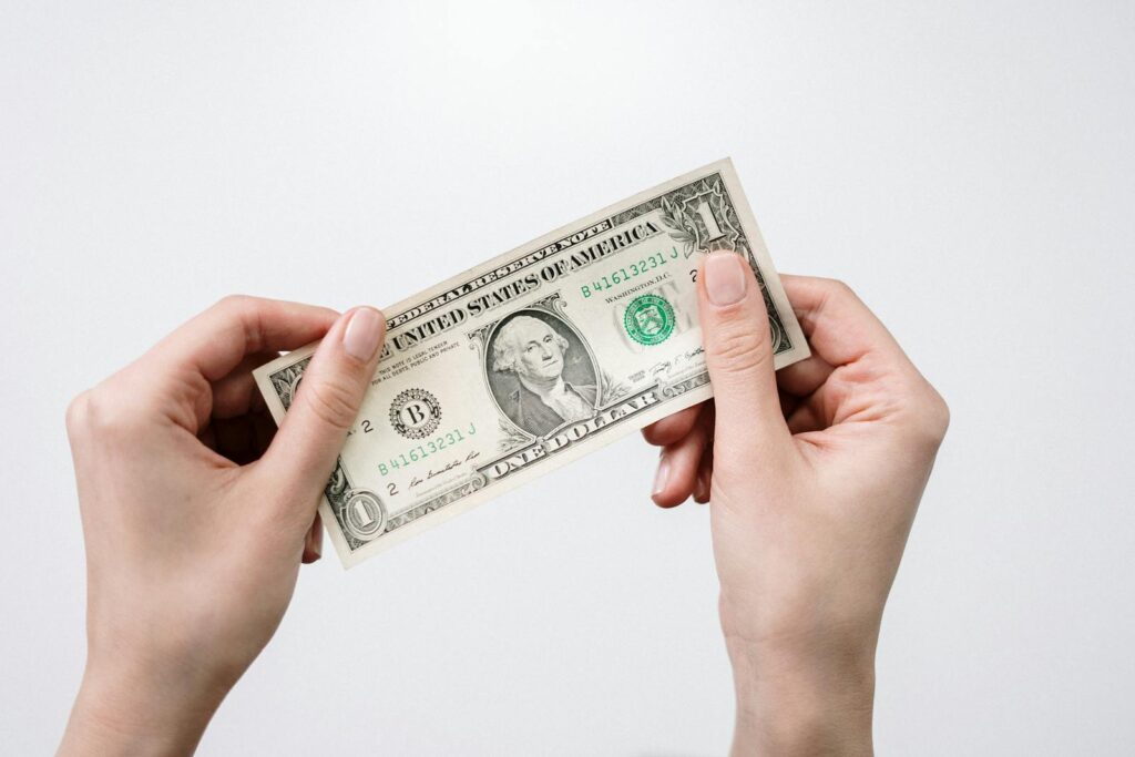 Hands holding a one dollar bill, depicting currency and finance closely.